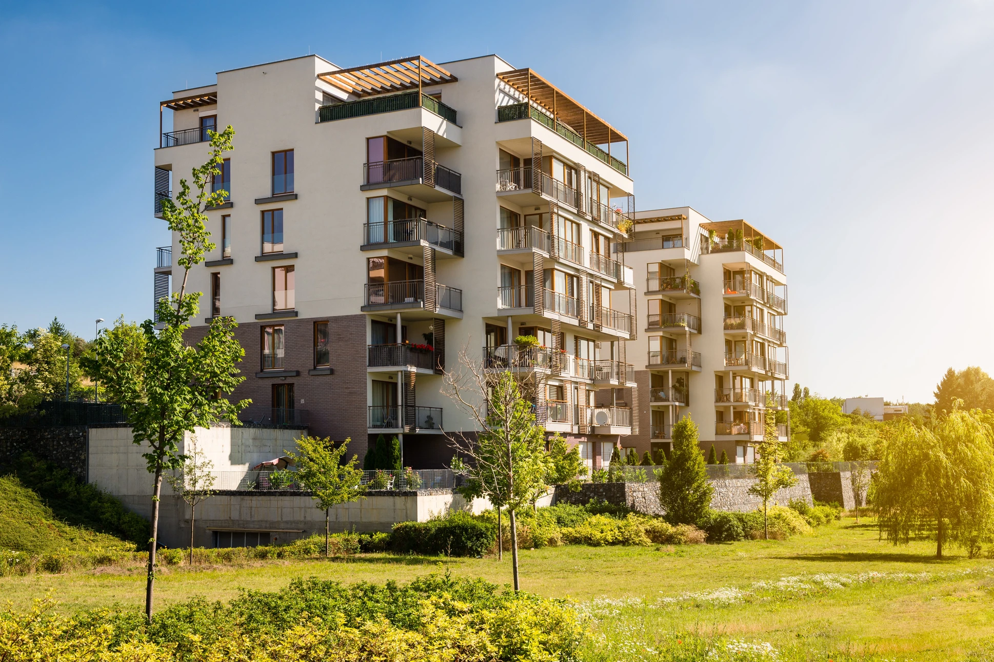 Résidence moderne multi-étages avec balcons et terrasses végétalisées, située dans un environnement paysager verdoyant